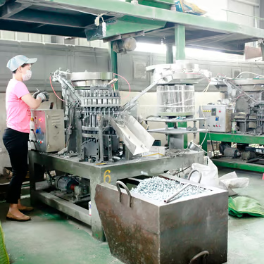 An operator beside production equipment and parts bins
