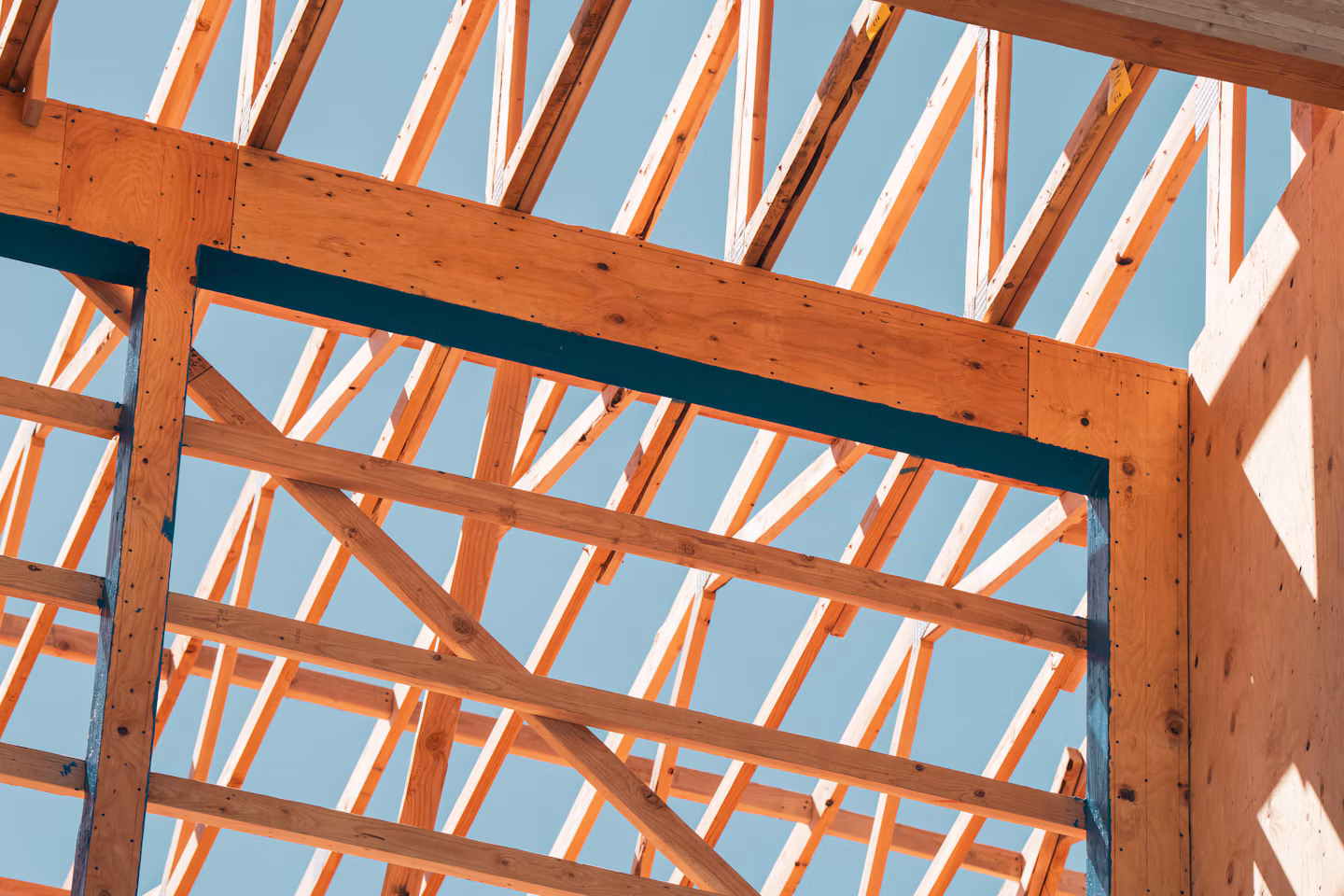 Timber roof framing against a blue sky